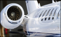 Close-up of passenger windows and jet engine of corporate jet.