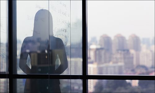 Silhouette shadow of woman looking at city from office