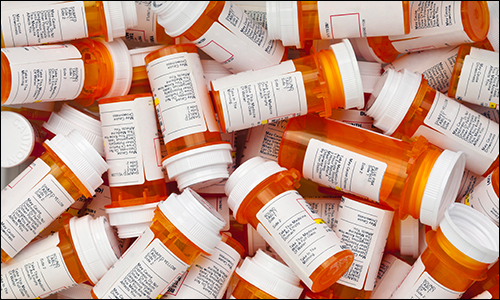 White pharmaceutical pills spilling from prescription bottle