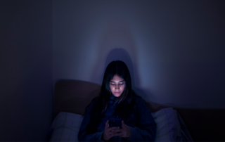 Teenage girl using a smartphone lying in bed late at night, playing games, watching videos, and typing. Children's screen addiction. Screen Addiction in Youth
