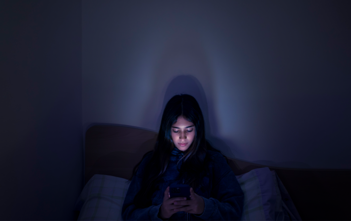 Teenage girl using a smartphone lying in bed late at night, playing games, watching videos, and typing. Children's screen addiction. Screen Addiction in Youth